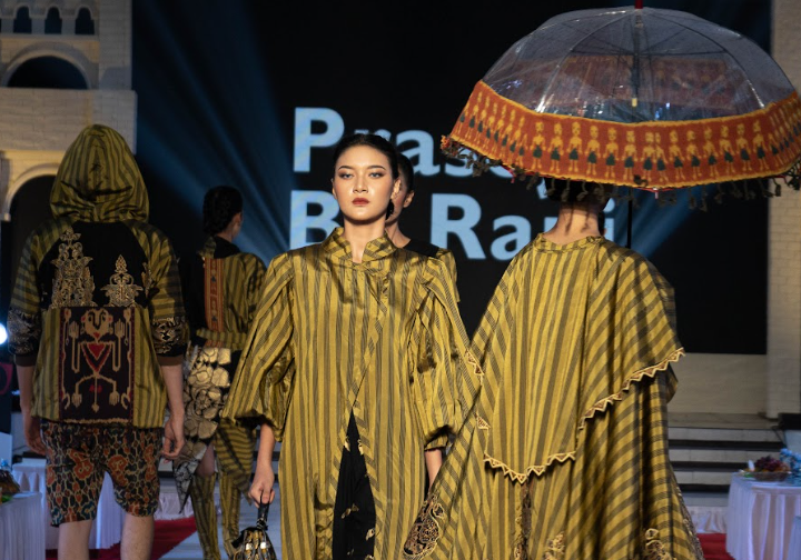 Model-model Prasojo by Rani melenggak-lenggok di catwalk menggunakan busana lurik keemasan